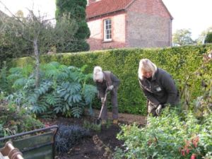 Gardeners Jenny and Janet digging over and mulching the 'Red Border'